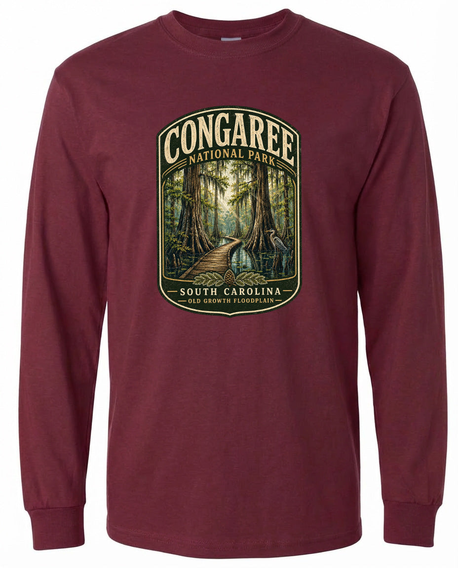 A long-sleeved burgundy t-shirt with a graphic design depicting a forest path leading through a lush, green landscape.
