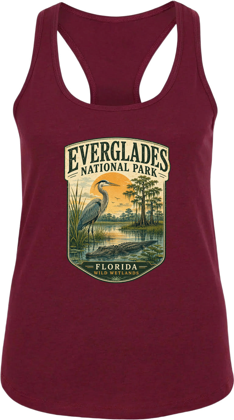 A maroon tank top with a graphic design depicting a bird standing in a marshy area with a sunset in the background, surrounded by trees and water.