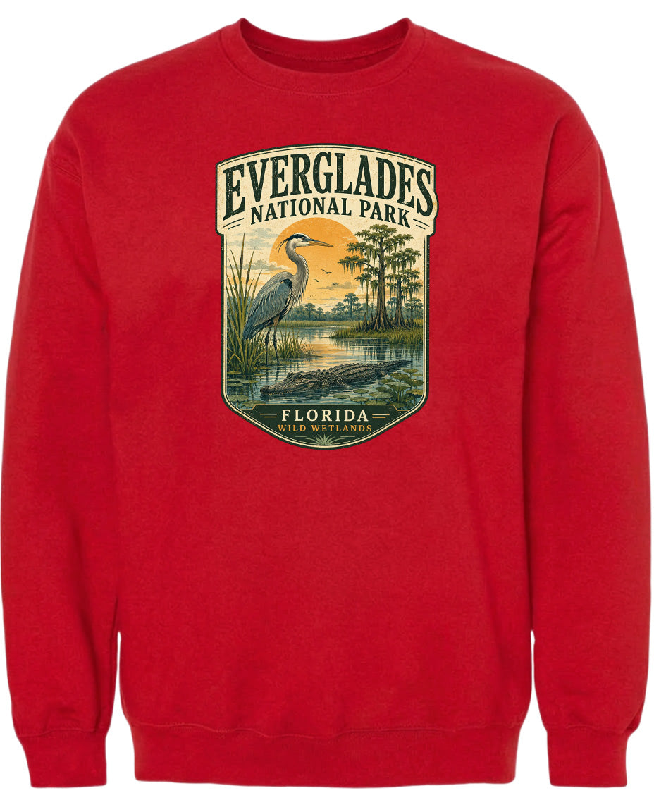 A red sweatshirt with a graphic design depicting Everglades National Park, including a bird, a pond, and trees.