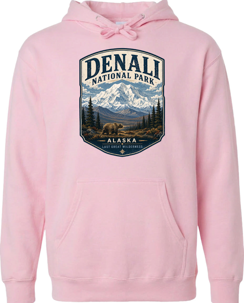 A pink hoodie with a graphic design depicting a mountain landscape and a bear, representing Denali National Park in Alaska.