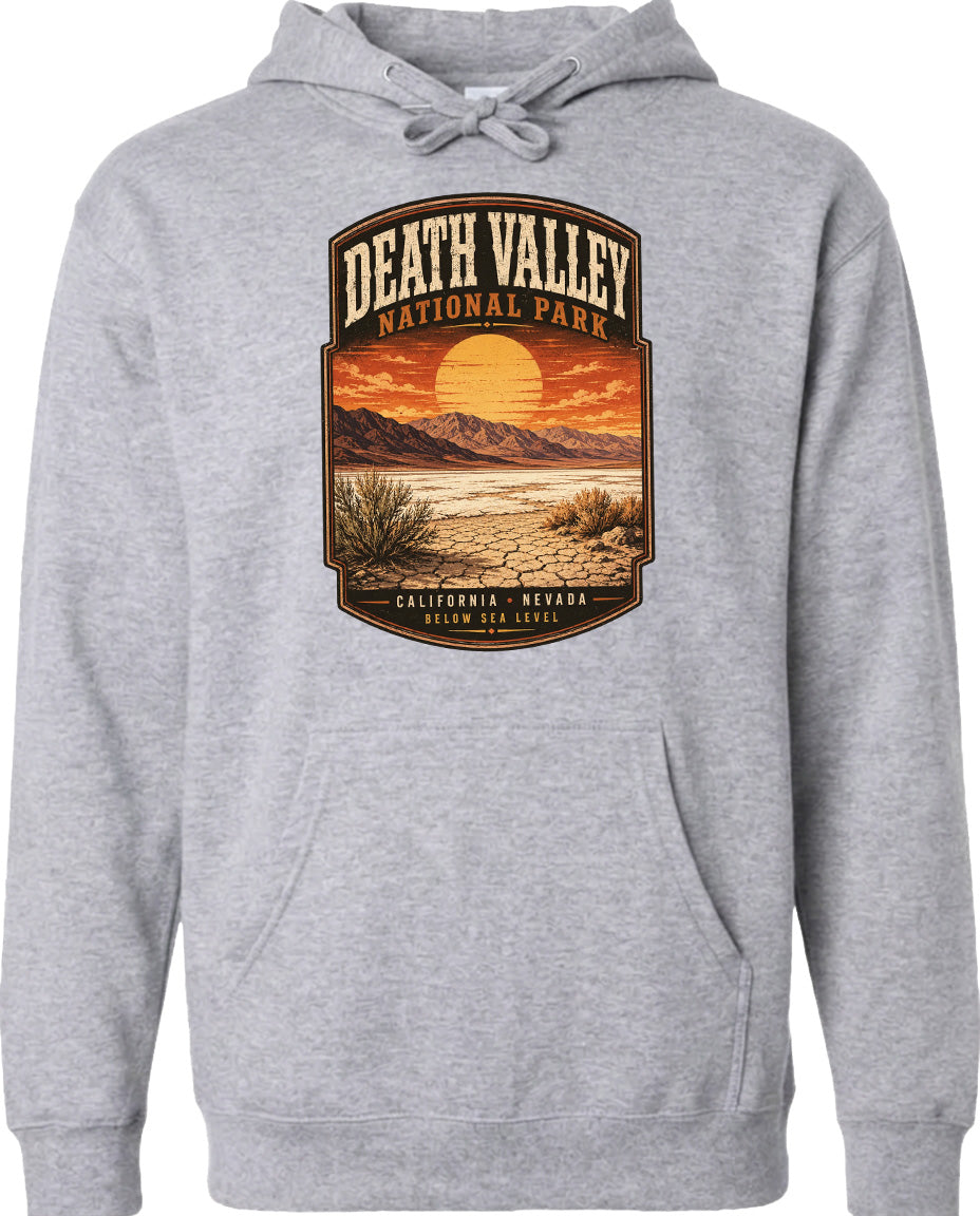 A gray hoodie with a graphic design depicting Death Valley National Park, including a sunset, mountains, and desert landscape.