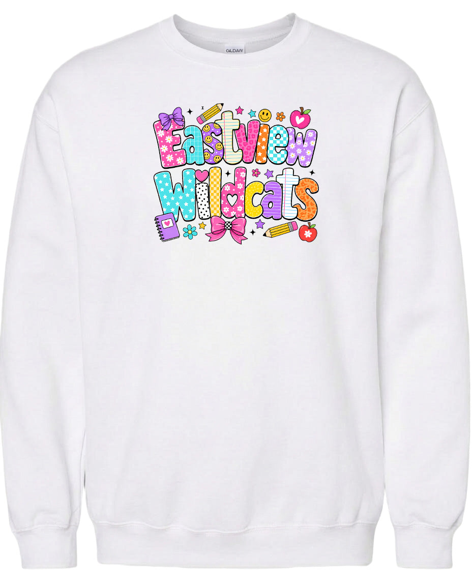 A white sweatshirt with a colorful graphic design featuring the text "Eastview Wildcats" and various decorative elements such as stars, hearts, and a pencil.