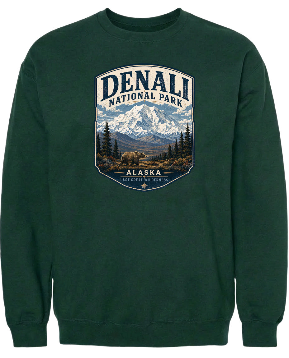 A green sweatshirt with a graphic design depicting Denali National Park in Alaska, featuring a mountain landscape with a bear in the foreground.