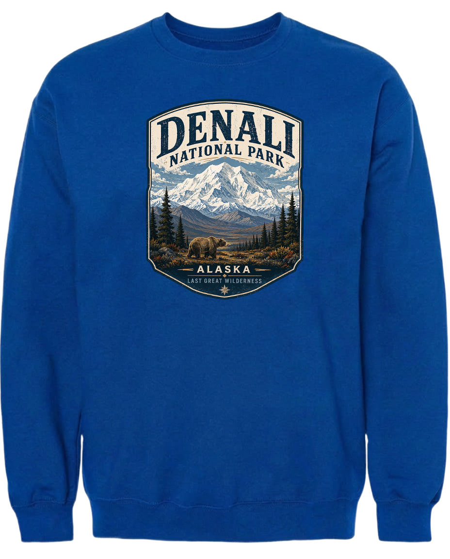 A blue sweatshirt with a graphic design depicting a mountain landscape with a bear in the foreground, surrounded by pine trees and mountains.