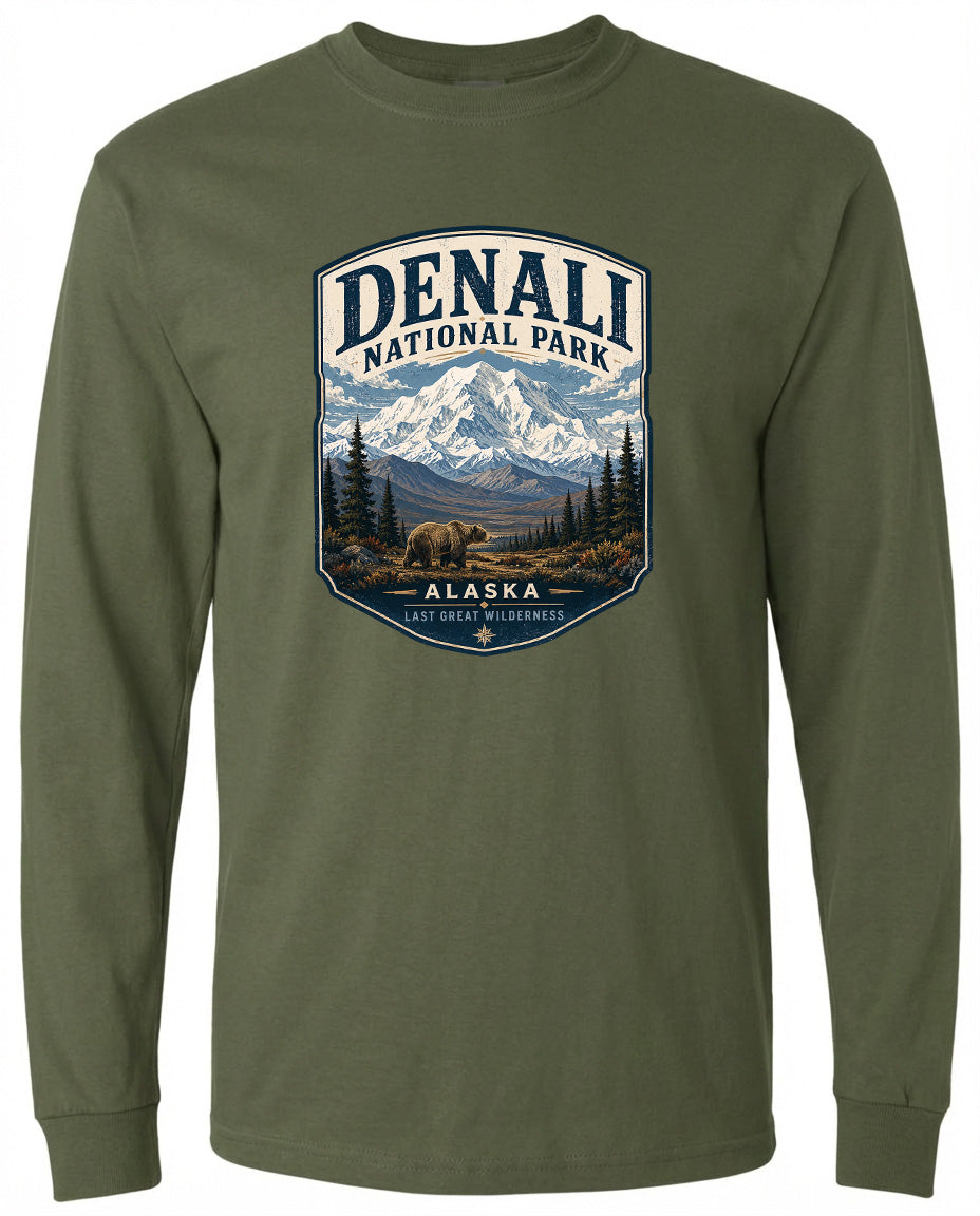 A green long-sleeved t-shirt with a graphic design depicting a bear in the foreground and a mountain range in the background, along with the text "DENALI NATIONAL PARK ALASKA LAST GREAT PLEASANCE".