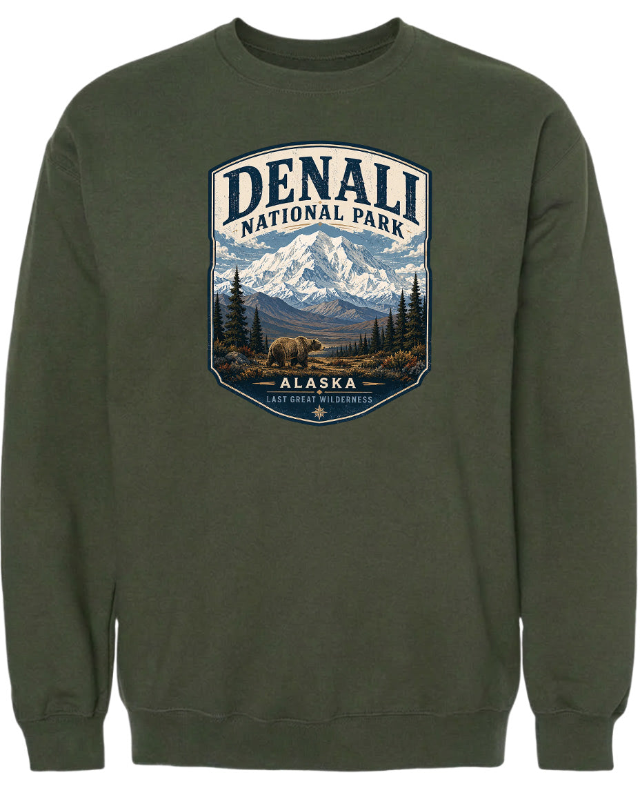 A green sweatshirt with a graphic design depicting a mountain landscape with a bear in the foreground, surrounded by pine trees and mountains.