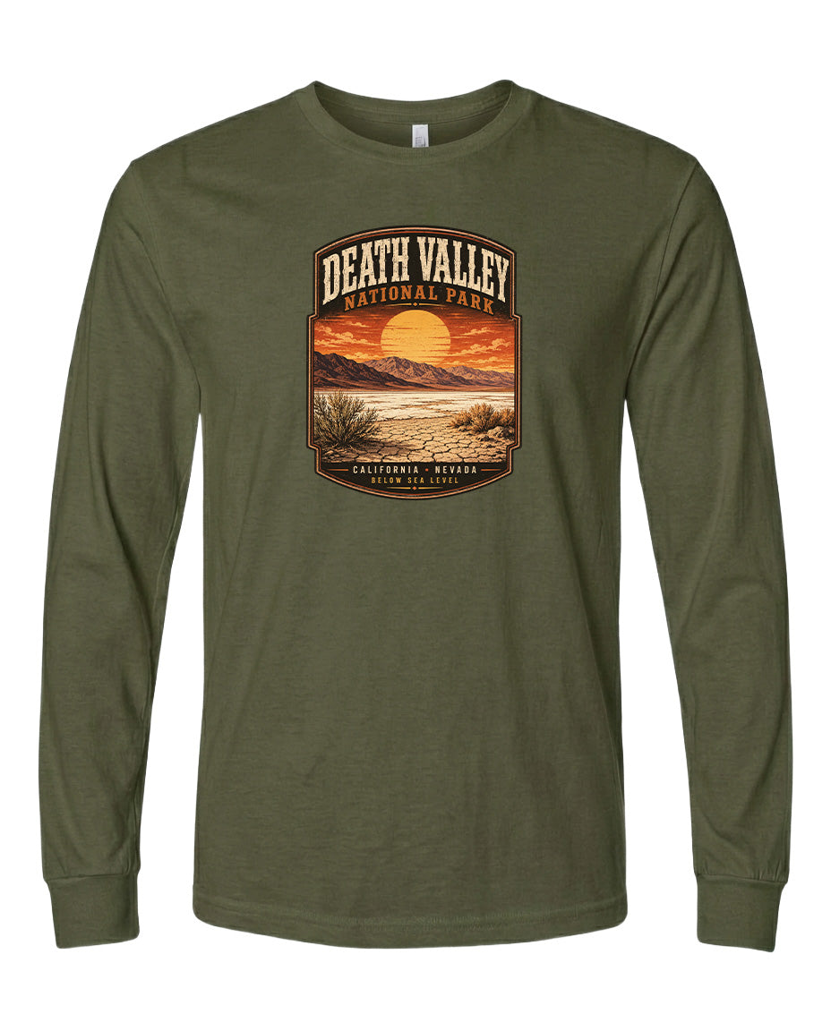 A long-sleeved olive green t-shirt with a graphic design depicting a desert landscape with a sunset and mountains in the background.