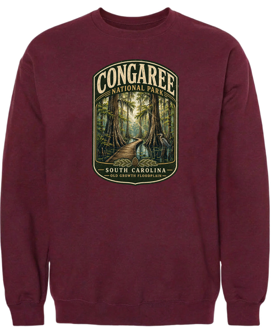 A burgundy sweatshirt with a graphic design depicting a forest scene, featuring a path leading through the trees and a bird in flight.