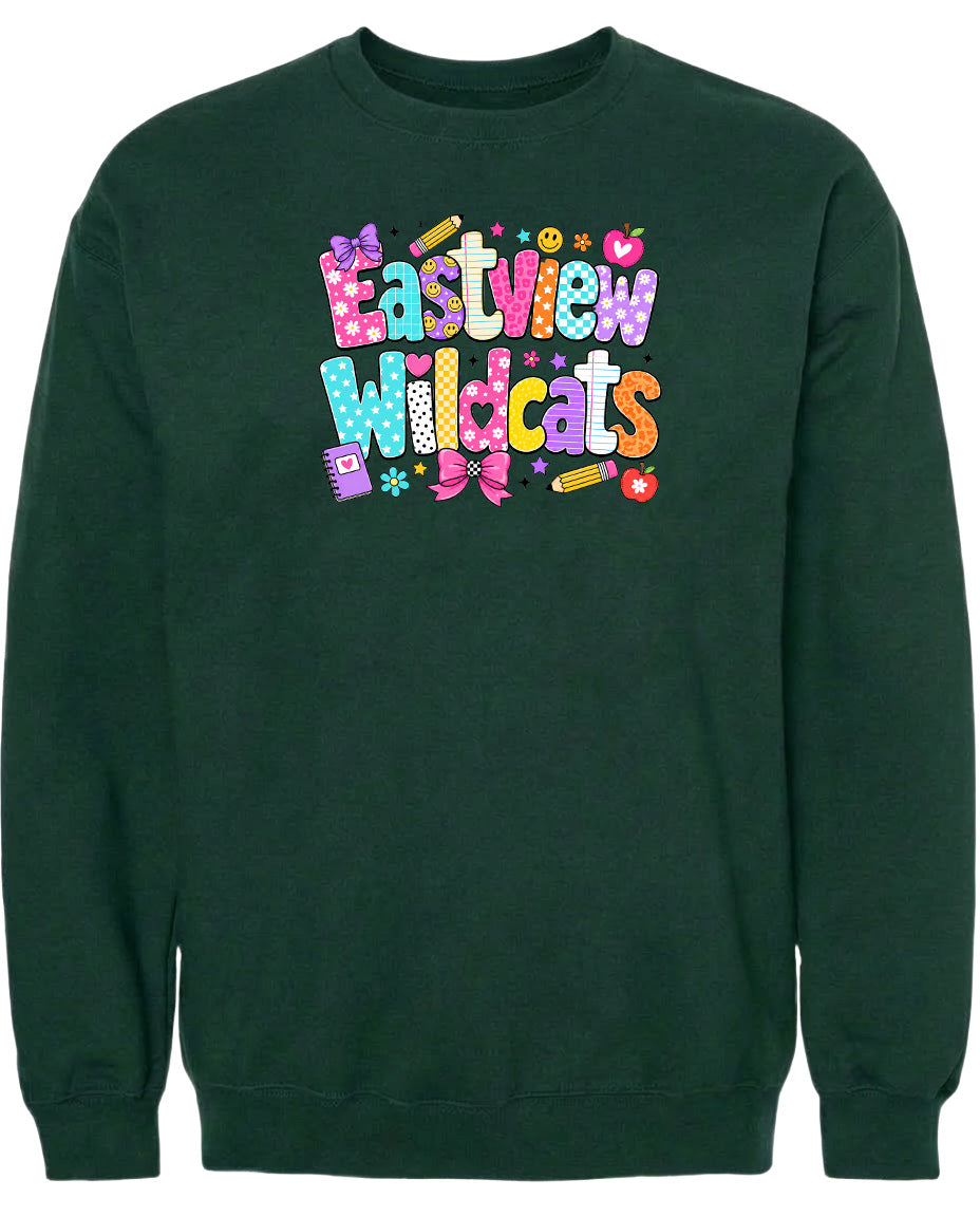 A dark green sweatshirt with a colorful, playful design featuring the text "Eastview Wildcats" and various decorative elements such as stars, hearts, and pencils.