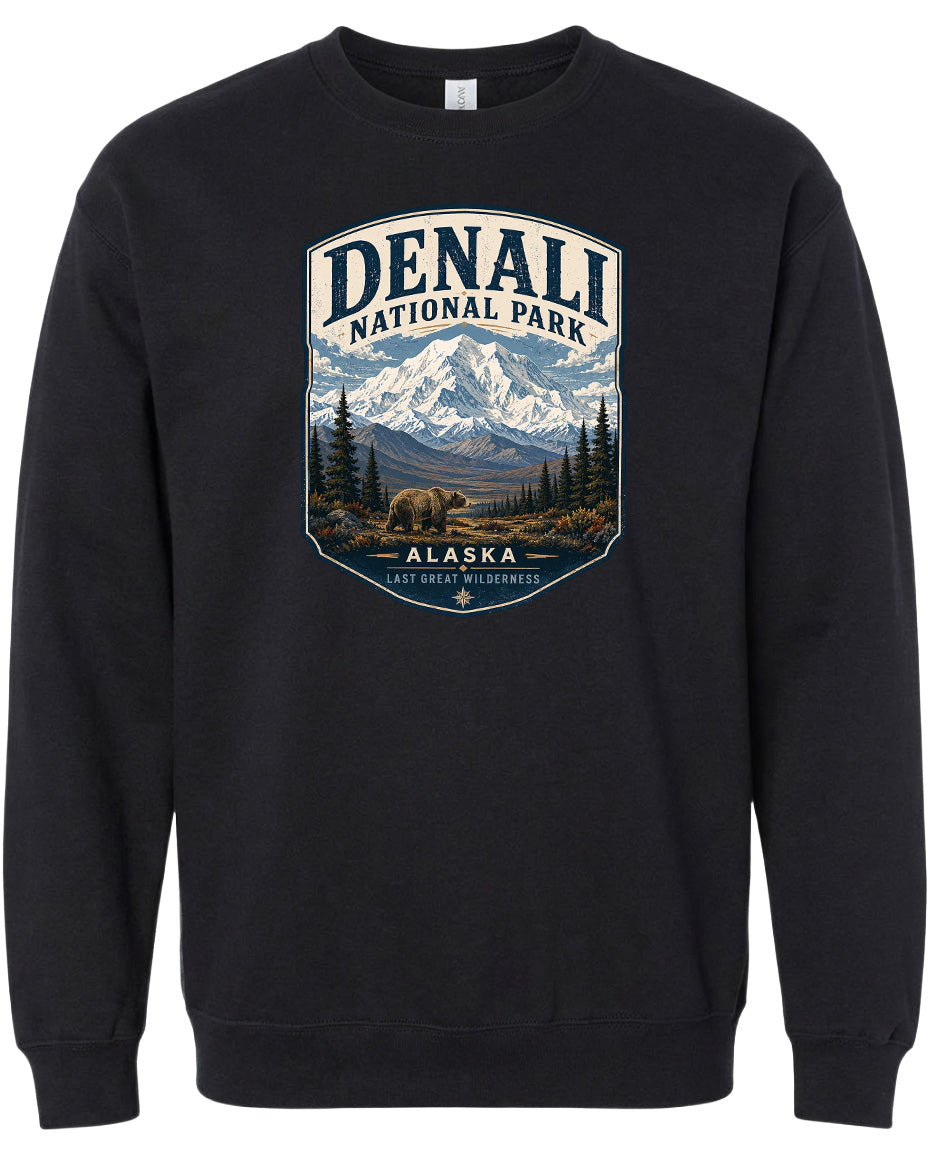 A black sweatshirt with a graphic design depicting a mountain landscape with a bear in the foreground, surrounded by pine trees and mountains.