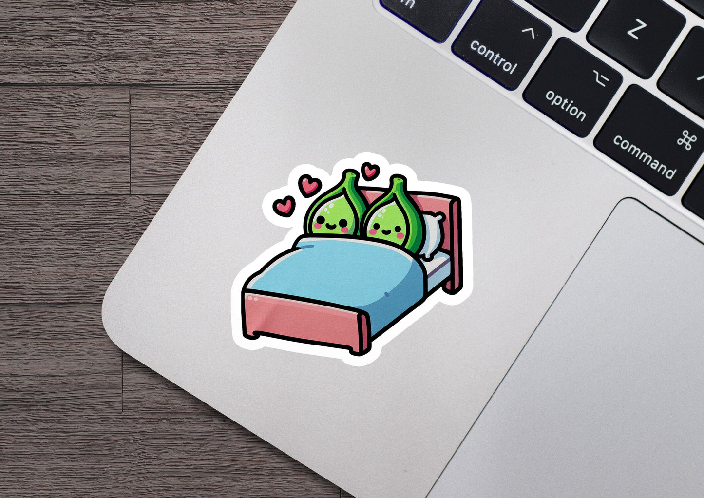a laptop with a sticker of two green birds in bed