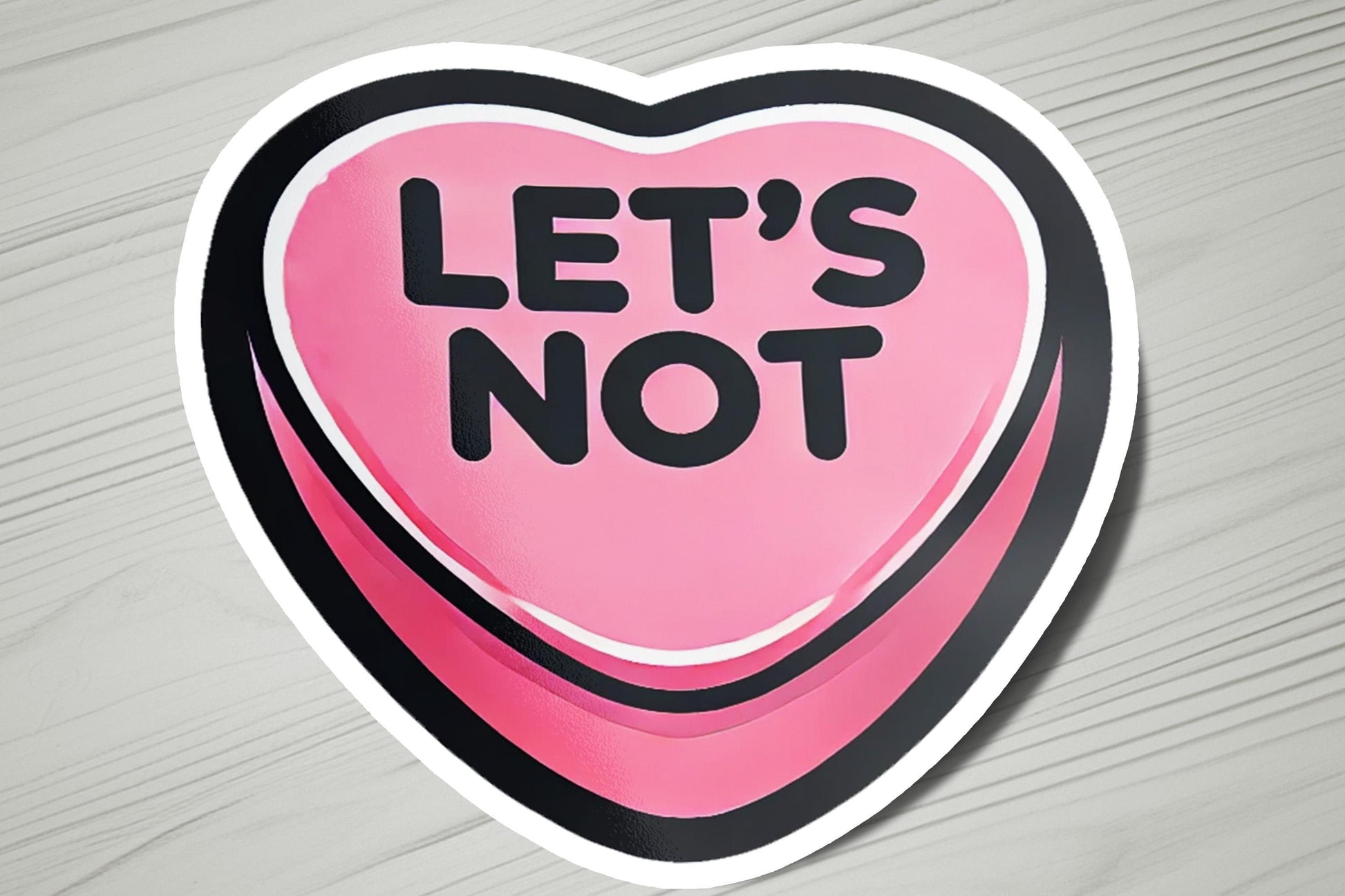 a pink heart shaped sticker that says let's not