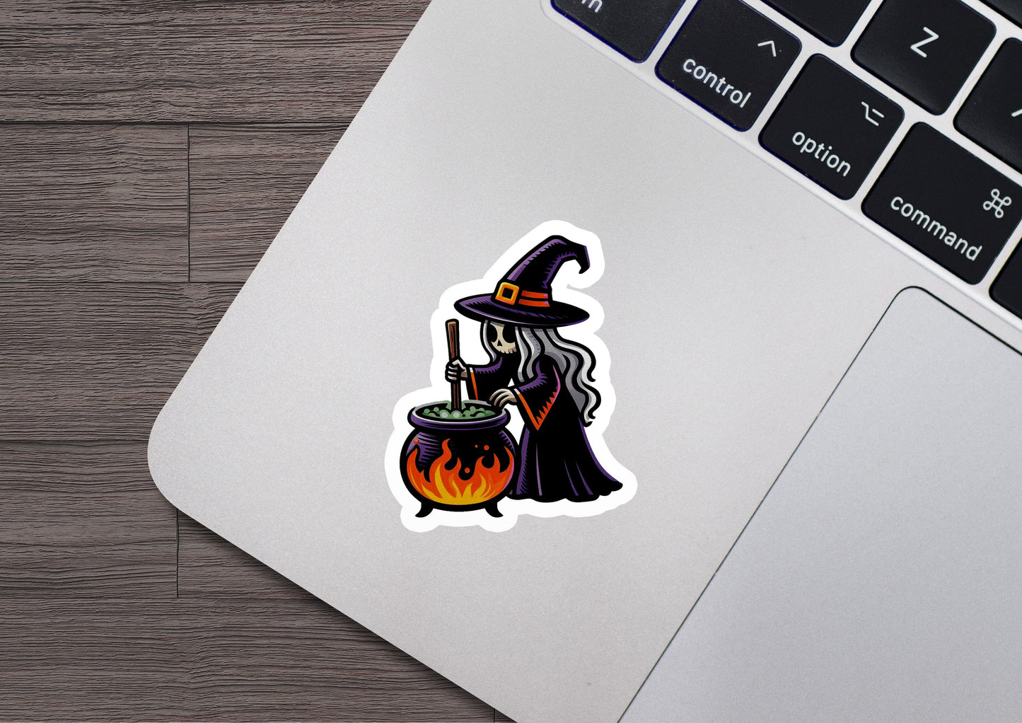 a laptop with a sticker of a witch holding a caulder