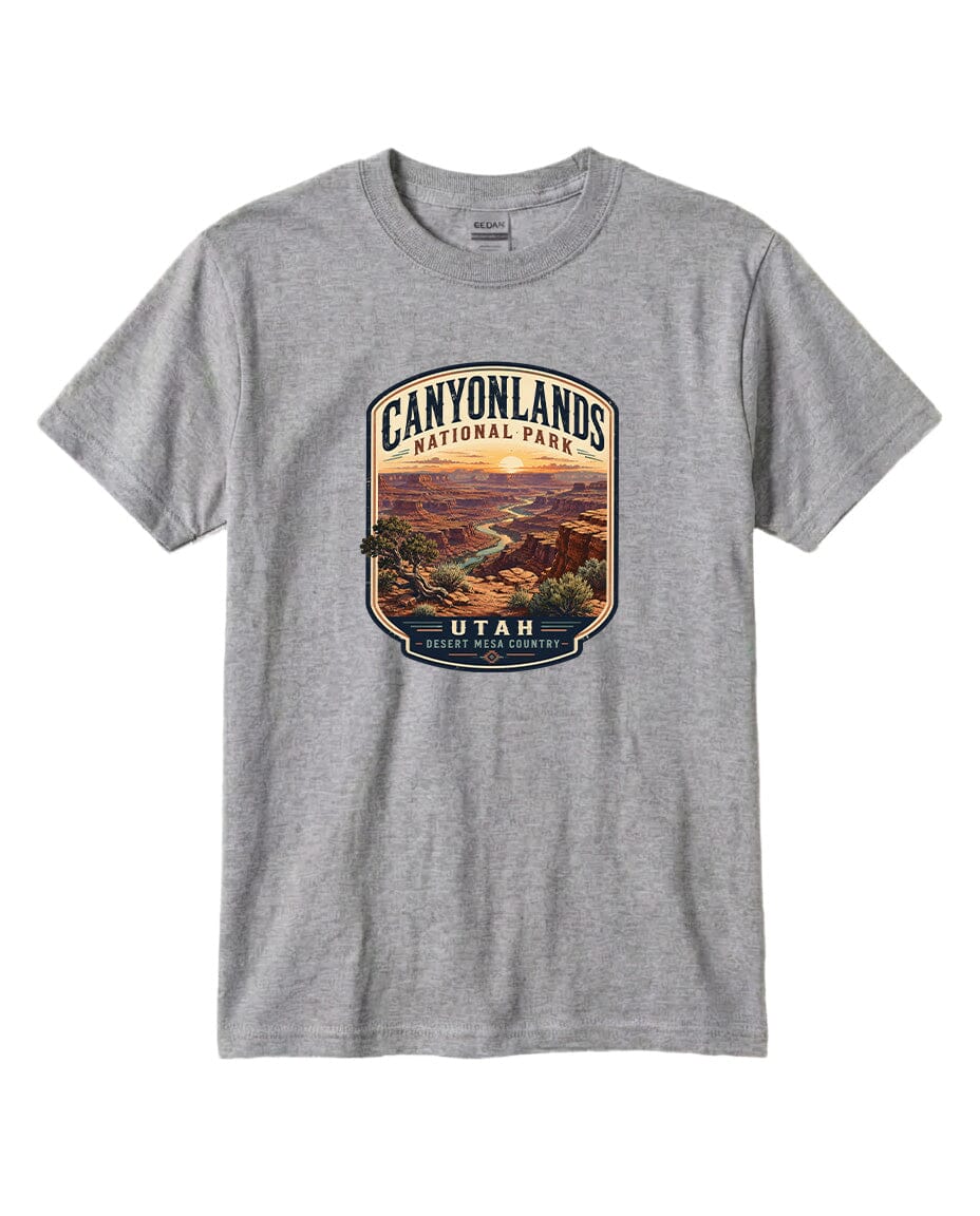 A gray t-shirt with a graphic design depicting a scenic landscape, including mountains, a river, and a sunset. The text on the design reads "CANYONLANDS NATIONAL PARK UTAH DESERT MESA COUNTY".
