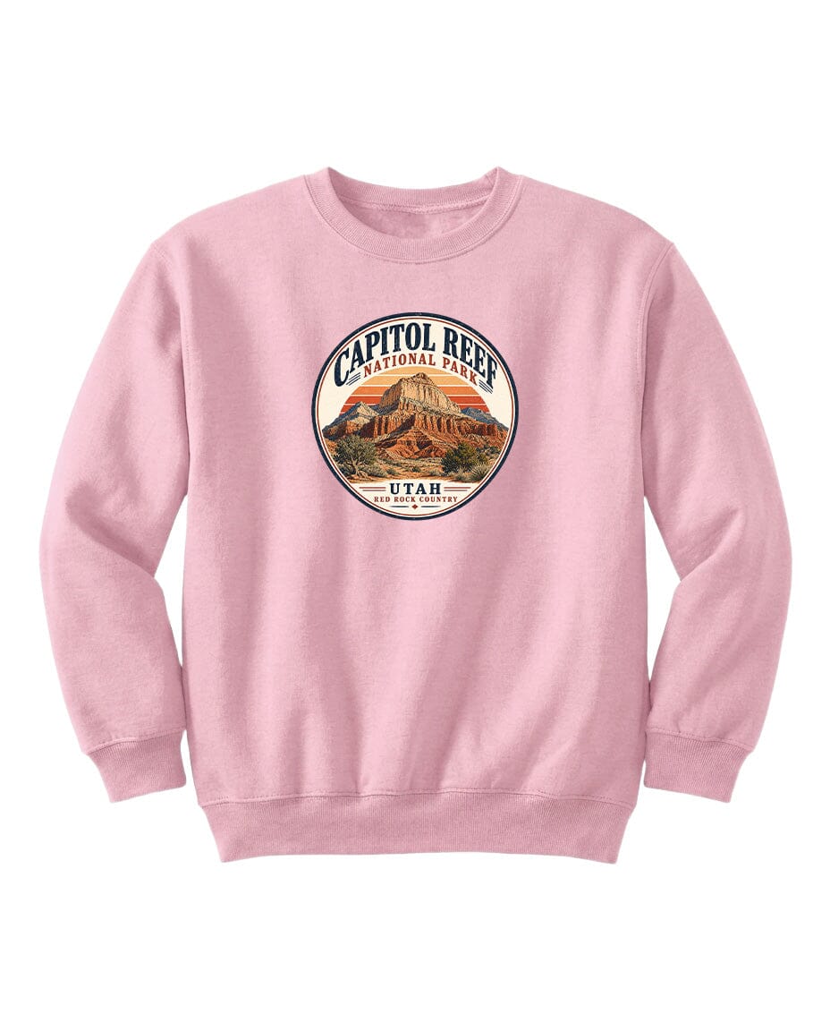 A pink sweatshirt with a circular design featuring a mountain and the text "CAPITOL REEF NATIONAL PARK UTAH" printed on it.