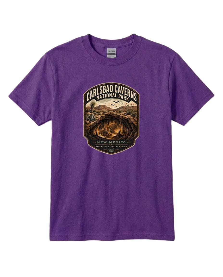 A purple t-shirt with a graphic design featuring a shield-shaped emblem that says "CARLSBAD CAVENS NATIONAL PARK NEW MEXICO UNDERGROUND WONDERS".