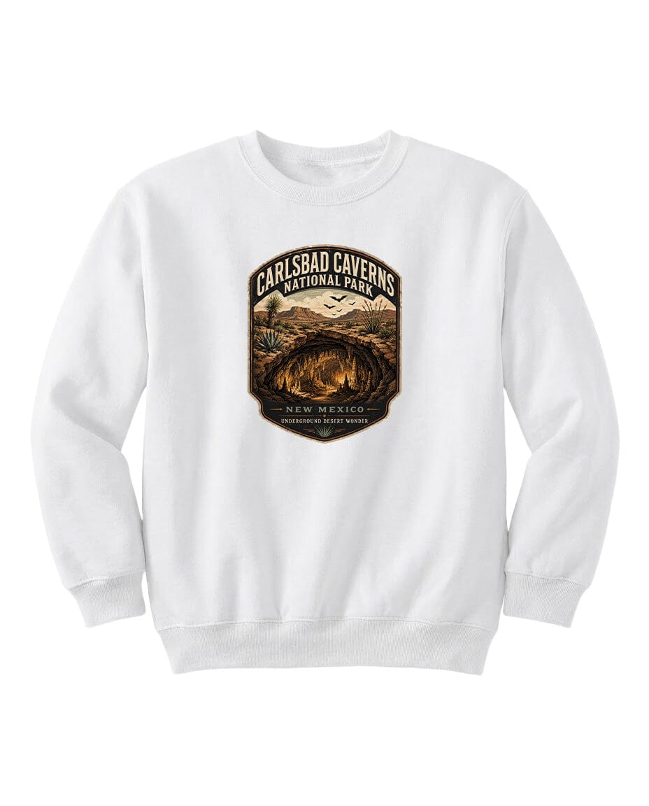 A white sweatshirt with a graphic design featuring a desert landscape and the text "CARLSBAD CAVENS NATIONAL PARK NEW MEXICO UNDERGROUND WONDER".