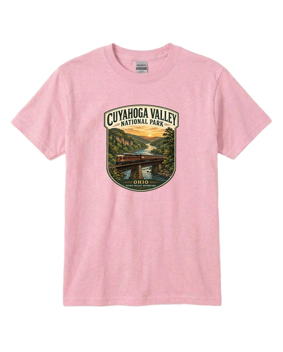 A pink t-shirt with a graphic design depicting a scenic view of the Cuyaohoga Valley National Park, featuring a bridge, river, and sunset.
