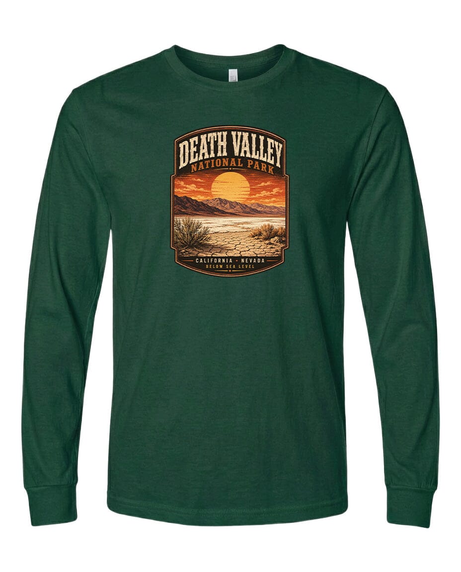 A long-sleeved green t-shirt with a graphic design depicting a desert landscape with a sunset and mountains in the background.