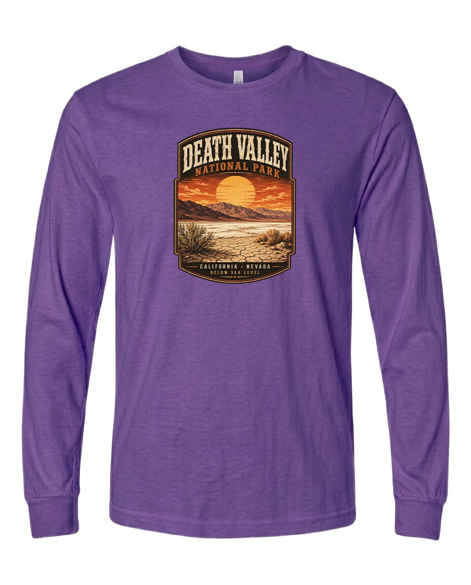 A purple long-sleeved t-shirt with a graphic design depicting a desert landscape with a sunset and mountains in the background.