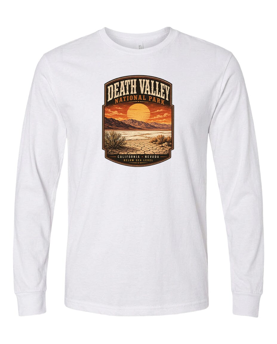 A white long-sleeved t-shirt with a graphic design depicting a desert landscape with a sunset and mountains in the background.