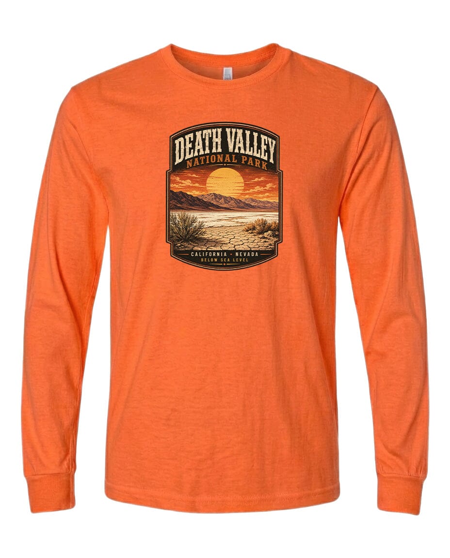 An orange long-sleeve t-shirt with a graphic design depicting a desert landscape with a sunset and mountains in the background.