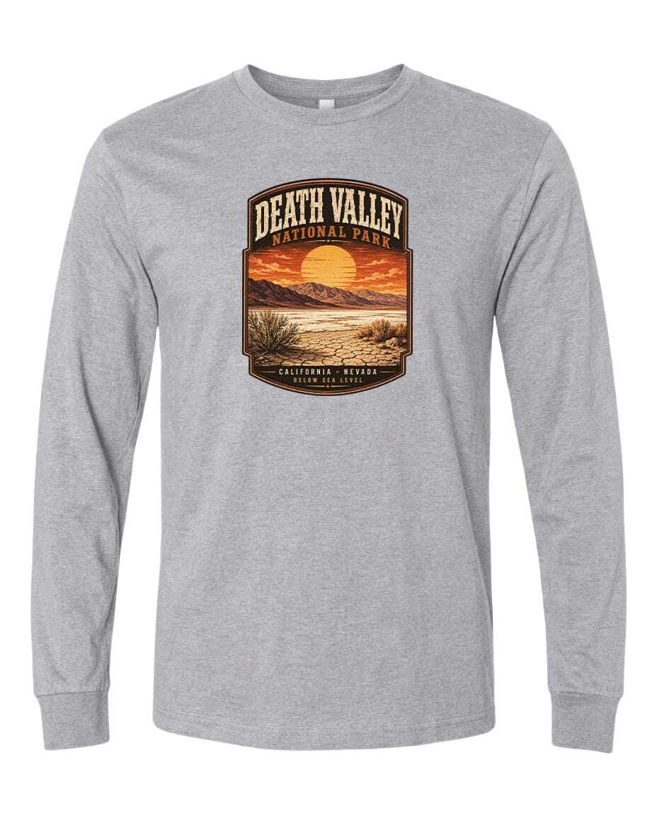 A gray long-sleeve t-shirt with a graphic design depicting a desert landscape with a sunset and mountains in the background.