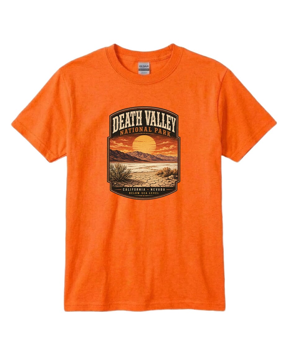 An orange t-shirt with a graphic design depicting a desert landscape with a sunset and mountains in the background.
