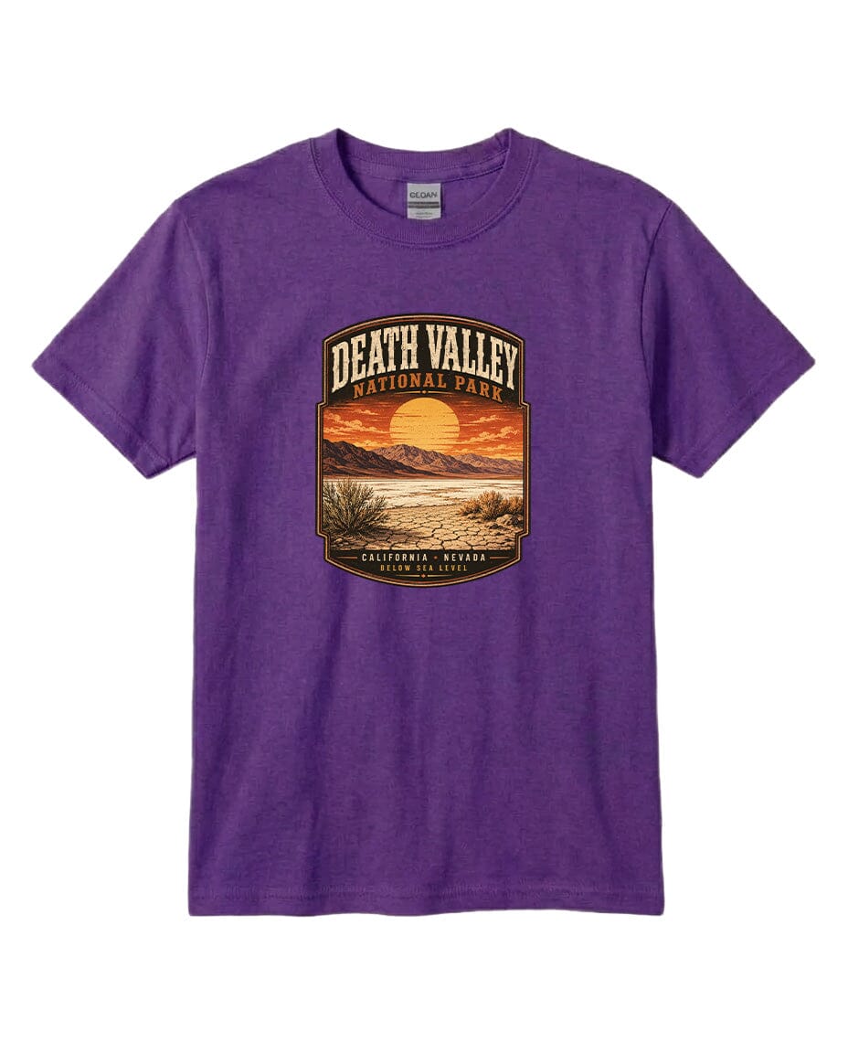 A purple t-shirt with a graphic design depicting Death Valley National Park, including a sunset, mountains, and desert landscape.