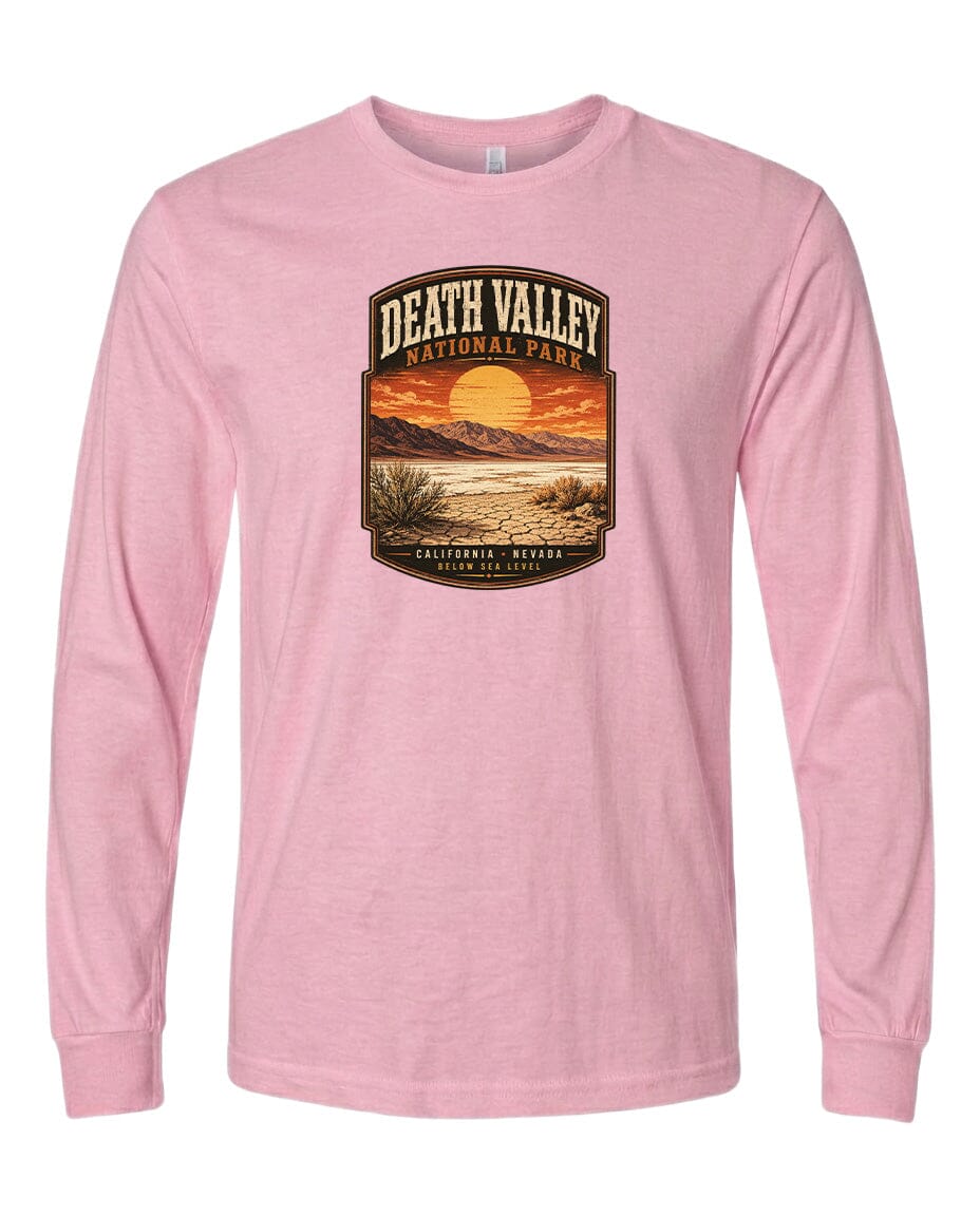 A pink long-sleeved t-shirt with a graphic design depicting a desert landscape with a sunset and mountains in the background.
